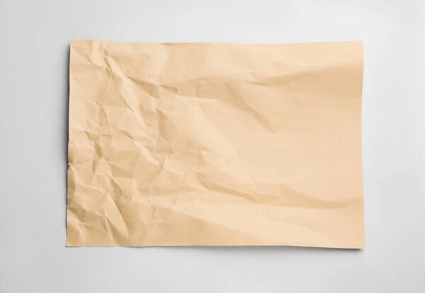 Sheet of crumpled brown paper on white background, top view