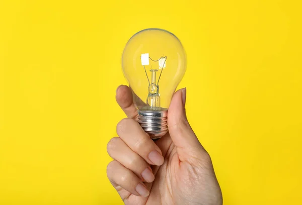 Mujer Sosteniendo Bombilla Incandescente Sobre Fondo Amarillo Primer Plano — Foto de Stock