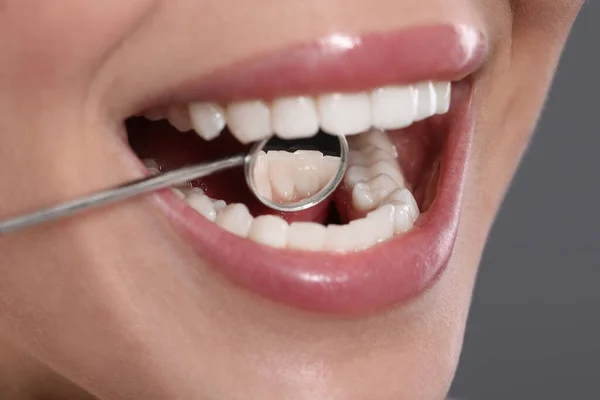 Badanie Zębów Kobiety Lustrem Dentystycznym Szarym Tle Zbliżenie — Zdjęcie stockowe
