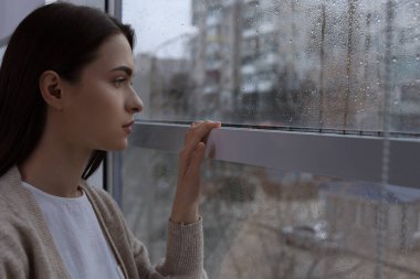 Yağmurlu bir günde pencereden dışarı bakan melankolik genç bir kadın, mesaj için yer var. Yalnızlık kavramı