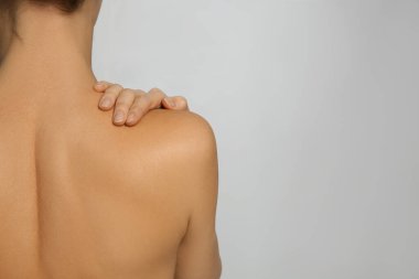 Açık gri arka planda kusursuz pürüzsüz bir cilde sahip bir kadının arka plan görüntüsü, yazı için boşluk. Güzellik ve vücut bakımı