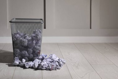 Beyaz duvarın yanında yerde kâğıt olan çöp tenekesi, mesaj için yer. Çöp geri dönüşümü