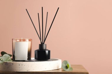 Pembe duvarın yanındaki ahşap masa üzerinde aromatik kamış oda spreyi ile kompozisyon, metin için boşluk