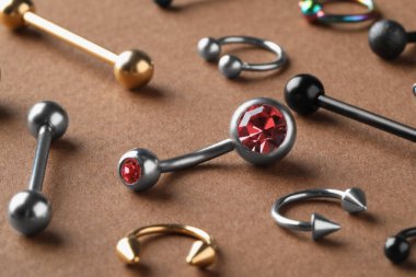 Kahverengi arka planda piercing için şık mücevherler, yakın plan.