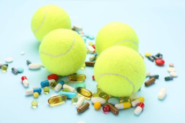 Tenis topları ve açık mavi arka planda farklı haplar. Doping kavramı