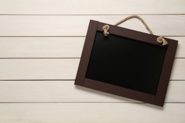 Beyaz ahşap masadaki temiz, küçük siyah karatahta, üst manzara. Metin için boşluk