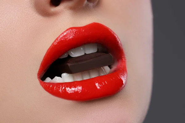 Młoda Kobieta Pięknymi Ustami Jedząca Czekoladę Szarym Tle Zbliżenie — Zdjęcie stockowe