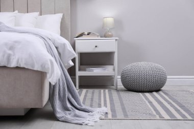 Şık bir yatak odası. Örgü pouf ve mobilyalarla dolu.