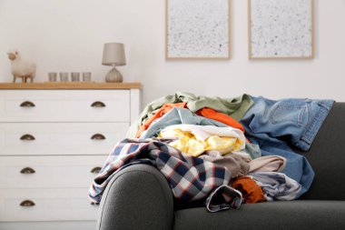 Oturma odasındaki kanepede kirli giysiler yığını. Yöntem düzenleniyor