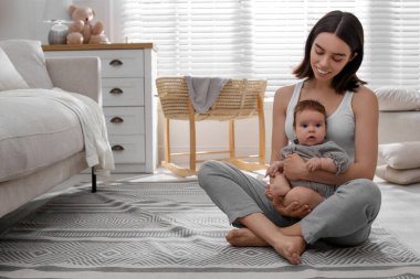 Küçük bebeği evde yerde yatan genç bir kadın.