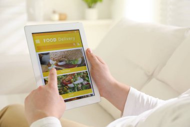 Evde yemek siparişi vermek için tablet kullanan bir adam, yakın çekim. Teslimat servisi