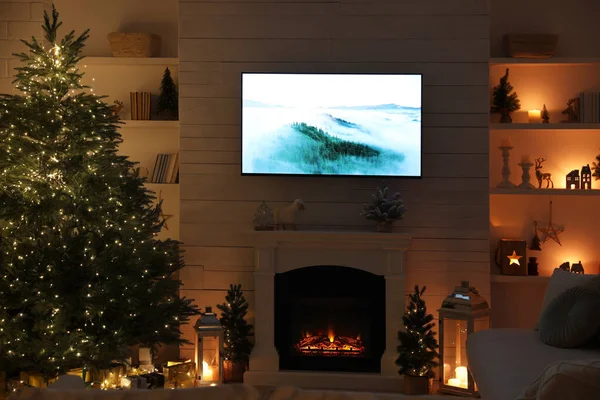 Stylish living room interior with TV set, Christmas tree and fireplace