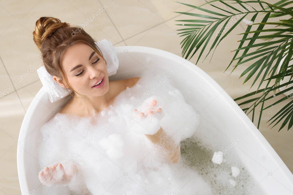 Beautiful woman enjoying bubble bath at home, above view