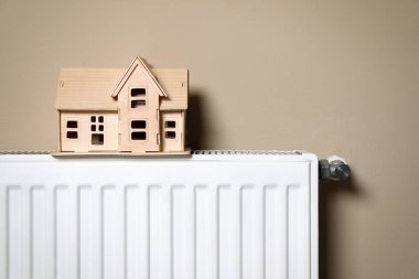 Bej duvarın yanında ahşap evi olan modern radyatör. Kış ısıtma etkinliği