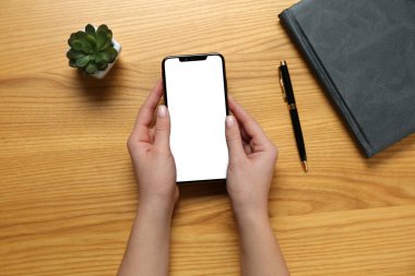 Ahşap masadaki akıllı telefonlu kadın, en iyi manzara.