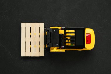 Siyah masa üzerinde ahşap paletli oyuncak forklift, üst görünüm