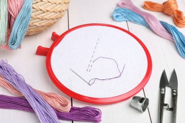 Beyaz ahşap masa üzerinde nakış aletleri.