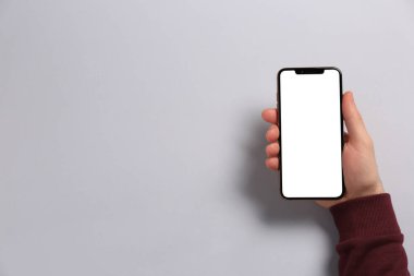 Açık gri arka planda akıllı telefonu olan bir adam. Metin için boşluk