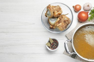 Lezzetli ev yapımı kemik suyu ve beyaz ahşap masa üzerindeki malzemeler, düz yatak. Metin için boşluk