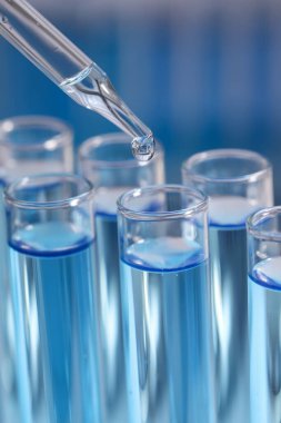 Bulanık arkaplanda test tüpüne reaktör damlatılıyor, yakın plan. Laboratuvar analizi