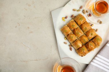 Fıstıklı enfes baklava ve açık gri masada sıcak çay. Metin için boşluk
