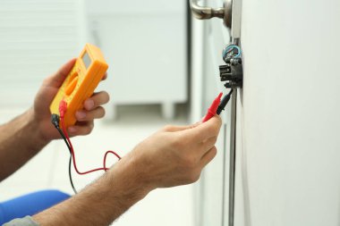 Profesyonel elektrikçi ışık düğmesini kontrol ediyor. Kapalı alanda, yakın plan.