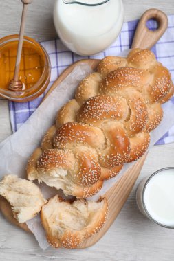 Kırık ev yapımı örülmüş ekmek beyaz ahşap masada, düz yerde. Geleneksel Şabat challah