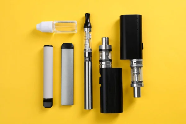Verschiedene Elektronische Zigaretten Und Dampfende Flüssigkeit Auf Gelbem Hintergrund Flache — Stockfoto