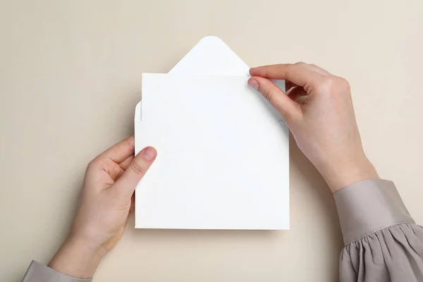 Woman Taking Card Out Envelope Beige Background Top View — Stock Photo, Image