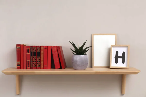 Półka Drewniana Różnymi Książkami Roślinami Domowymi Ramami Jasnej Ścianie — Zdjęcie stockowe