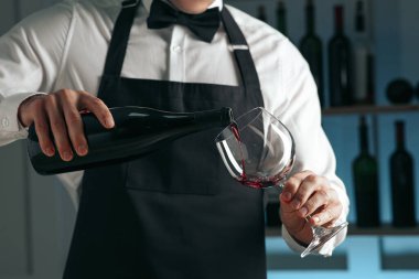 Barmen restoranda bardağa şarap dolduruyor.