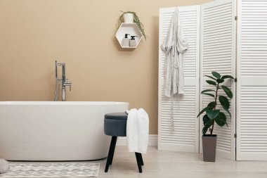 Şık bir seramik küvetin olduğu samimi banyo.