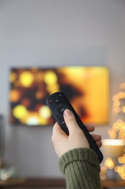 Noel için dekore edilmiş odada uzaktan kumandalı bir kadın, yakın plan.