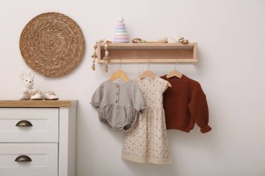 Mobilyaları, kıyafetleri ve aksesuarları olan bebek odası.