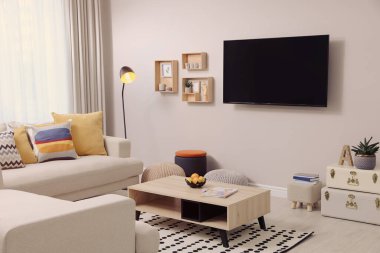 Modern TV, rahat kanepe ve dekorasyon malzemeleri oturma odasında.