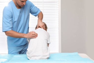 Ortopedist, çocuğun muayenesini klinikte yapıyor. Skolyoz tedavisi