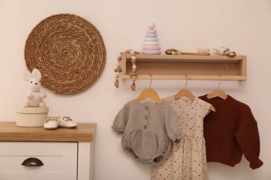 Mobilyaları, kıyafetleri ve aksesuarları olan bebek odası.