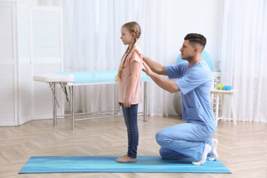 Ortopedist, çocuğun muayenesini klinikte yapıyor. Skolyoz tedavisi