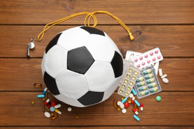 Futbol topu, ıslık ve tahta masada farklı haplar. Doping kavramı