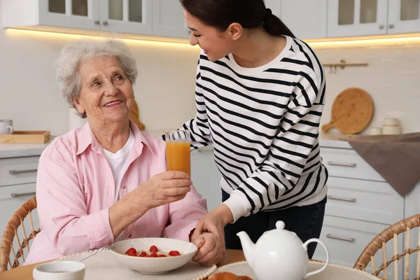 Young Caregiver Serving Breakfast Senior Woman Table Kitchen Home Care — Stock Photo, Image