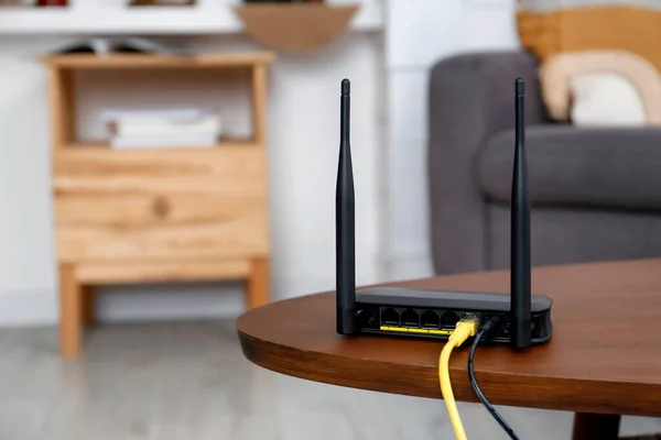 Modern Wi-Fi router on wooden table indoors. Space for text