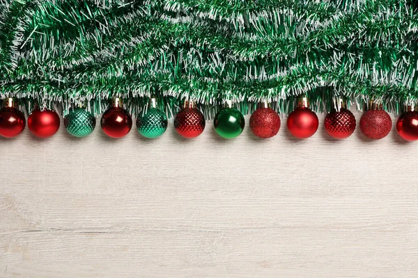白い木製の背景に緑のティンセルとクリスマスボール フラットレイアウト テキストのスペース — ストック写真