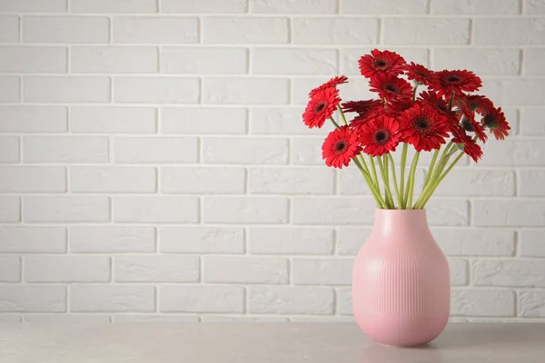 Beyaz Tuğla Duvarın Yanındaki Masada Bir Buket Güzel Kırmızı Gerbera — Stok fotoğraf