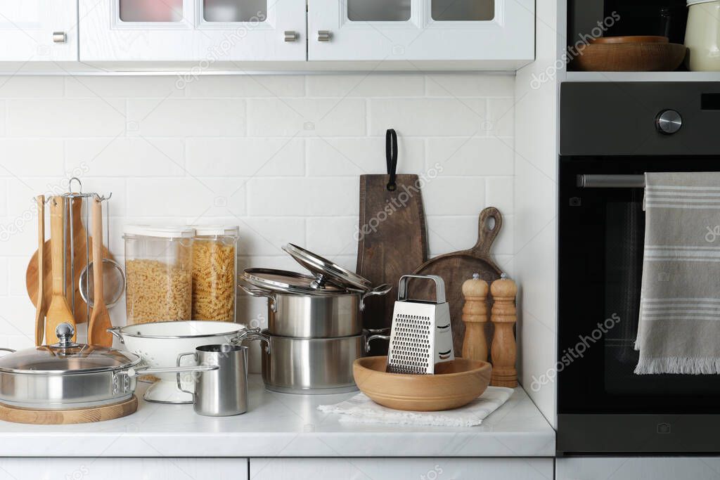 Different cooking utensils and raw pasta on countertop in kitchen