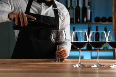 Barmen restoranda bardağa şarap dolduruyor.