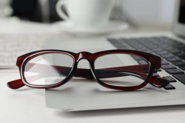 Modern laptop ve gözlükler beyaz masada, yakın plan.