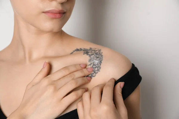 Mulher Aplicando Creme Tatuagem Sua Pele Contra Fundo Claro Close — Fotografia de Stock