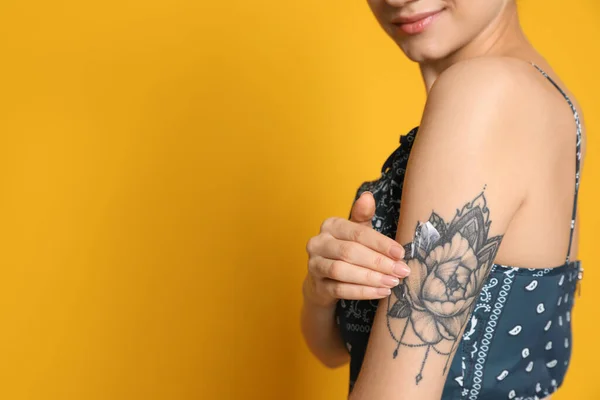 Donna Che Applica Crema Sul Braccio Con Tatuaggio Sfondo Giallo — Foto Stock