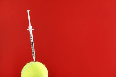 Kırmızı zemin üzerinde şırınga olan tenis topu, yazı için boşluk. Doping kavramı