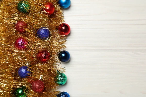 白い木製の背景にクリスマスボールと光沢のある黄金のティンセル フラットレイアウト テキストのスペース — ストック写真